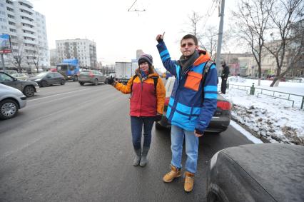 Путешествие автостопом. На снимке: молодые люди голосуют на шоссе.