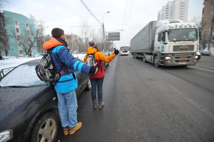 Путешествие автостопом. На снимке: молодые люди голосуют на шоссе.