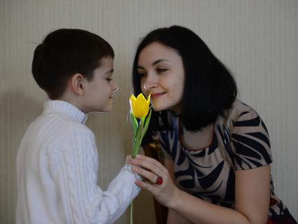 Дети и родители. На снимке: мальчик дарит маме тюльпан на 8 марта.