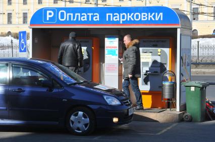 Водитель такси оплачивает парковку через терминал.