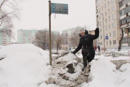 Неубранные тротуары. Женщина перелезает через завалы снега.