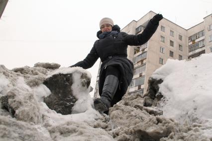 Неубранные тротуары. Женщина перелезает через завалы снега.