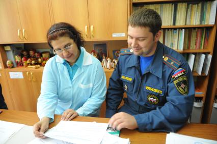 Сотрудники МЧС проводят проверку пожарной безопасности в столичных школах и детских садах перед началом учебного года. На снимке: и. о. начальника второго регионального отдела надзорной деятельности управления по ЮЗАО ГУ МЧС России по г. Москве  Николай Черкасов и сотрудница детского сада проверяют журнал регистрации инструктажей.