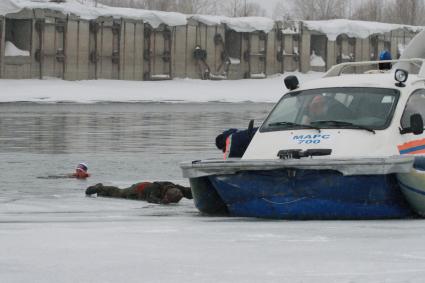 На реке Обь, в Барнауле проходят учения МЧС по спасению рыбаков. На снимке: спасатели вытаскивают из ледяной воды рыбака с спасательного судна МЧС на воздушной подушке `Марс 700`.