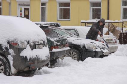 Водитель чистит автомобиль от снега.