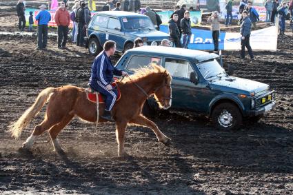 Шоу `Нива-35`. На снимке: мужчина на лошади скачет мимо проезжающего автомобиля.