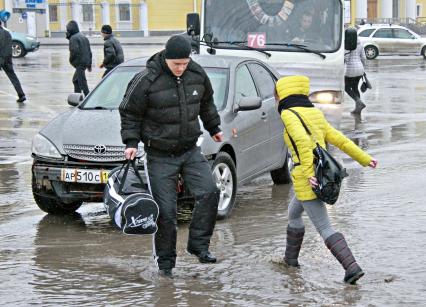 Пешеходы переходят дорогу по лужам