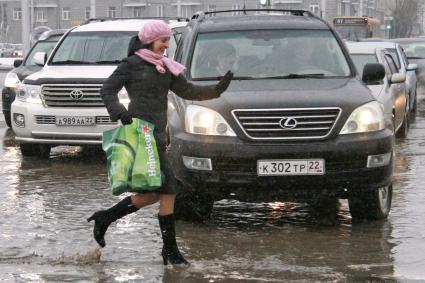 Девушка перебегает дорогу по лужам.