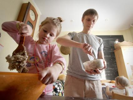 Девочка помогает готовить родителям на кухне.