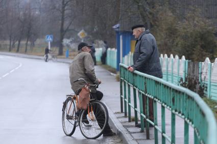 Двое мужчин разговаривают в деревне на улице в Беларуси.