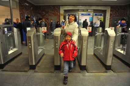 Московский метрополитен На снимке: пассажиры проходят в метро через турникет