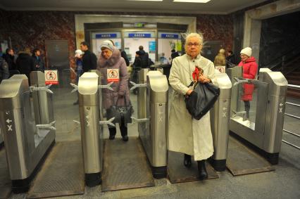 Московский метрополитен На снимке: пассажиры проходят в метро через турникет