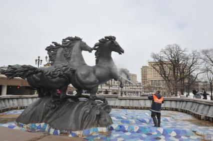 Манежная площадь. На снимке: сотрудник коммунальной службы города моет скульптурную группу `Времена года` фонтана \"Гейзер`.