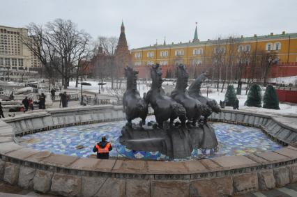 Манежная площадь. На снимке: сотрудник коммунальной службы города моет скульптурную группу `Времена года` фонтана \"Гейзер`.