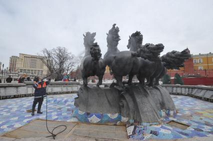 Манежная площадь. На снимке: сотрудник коммунальной службы города моет скульптурную группу `Времена года` фонтана \"Гейзер`.