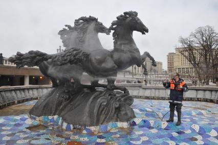 Манежная площадь. На снимке: сотрудник коммунальной службы города моет скульптурную группу `Времена года` фонтана \"Гейзер`.