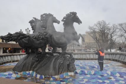 Манежная площадь. На снимке: сотрудник коммунальной службы города моет скульптурную группу `Времена года` фонтана \"Гейзер`.