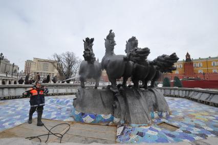 Манежная площадь. На снимке: сотрудник коммунальной службы города моет скульптурную группу `Времена года` фонтана \"Гейзер`.