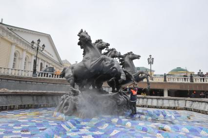 Манежная площадь. На снимке: сотрудник коммунальной службы города моет скульптурную группу `Времена года` фонтана \"Гейзер`.