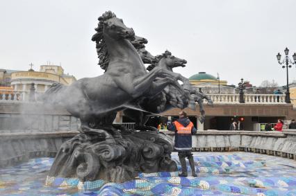 Манежная площадь. На снимке: сотрудник коммунальной службы города моет скульптурную группу `Времена года` фонтана \"Гейзер`.