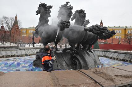 Манежная площадь. На снимке: сотрудник коммунальной службы города моет скульптурную группу `Времена года` фонтана \"Гейзер`.
