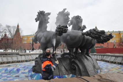 Манежная площадь. На снимке: сотрудник коммунальной службы города моет скульптурную группу `Времена года` фонтана \"Гейзер`.