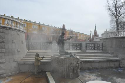 Манежная площадь. На снимке: сотрудник коммунальной службы города моет скульптуру по мотивам сказки `О рыбаке и рыбке`.