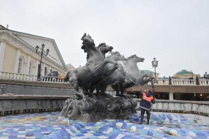 Манежная площадь. На снимке: сотрудник коммунальной службы города моет скульптурную группу `Времена года` фонтана \"Гейзер`.