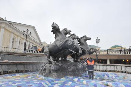 Манежная площадь. На снимке: сотрудник коммунальной службы города моет скульптурную группу `Времена года` фонтана \"Гейзер`.