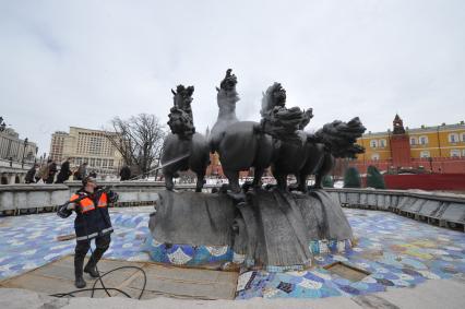 Манежная площадь. На снимке: сотрудник коммунальной службы города моет скульптурную группу `Времена года` фонтана \"Гейзер`.