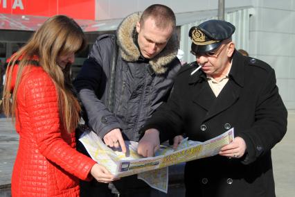 Три человека около вокзала изучают карту Москвы.