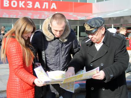 Три человека около вокзала изучают карту Москвы.