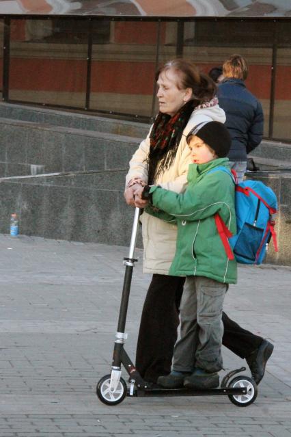 Пожилая женщина забирает внука из школы.