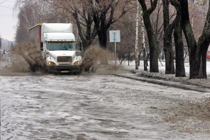 Весенние паводковые воды на улице города. Грузовик проезжает через затопленную водой улицу.