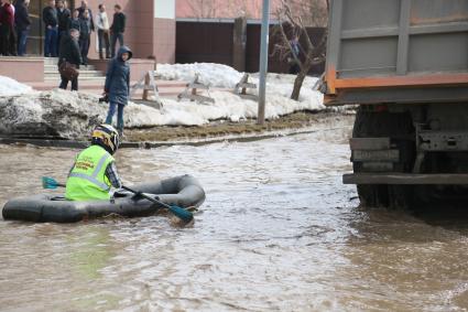 Из-за быстрого таяния снегов весенние паводковые воды затопили проезжую часть на улицах Казани. На снимке: мужчина в мотоциклетном шлеме и жилетке с надписью: `Общественный контроль` на резиновой лодке плывет по затопленной улице города.