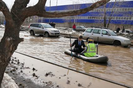 Из-за быстрого таяния снегов весенние паводковые воды затопили проезжую часть на улицах. На снимке: мужчины на резиновой лодке на затопленной улице.
