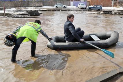 Из-за быстрого таяния снегов весенние паводковые воды затопили проезжую часть на улицах. На снимке: мужчина на резиновой лодке на затопленной улице.