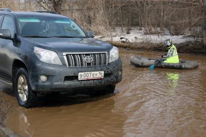 Из-за быстрого таяния снегов весенние паводковые воды затопили проезжую часть на улицах. На снимке: мужчина на резиновой лодке на затопленной улице.