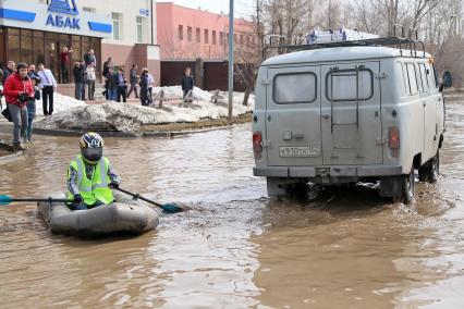 Из-за быстрого таяния снегов весенние паводковые воды затопили проезжую часть на улицах Казани. На снимке: мужчина в мотоциклетном шлеме на резиновой лодке плывет по затопленной улице города.