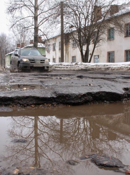 Ямы на дорогах в городе, автомобиль едет по ямам.