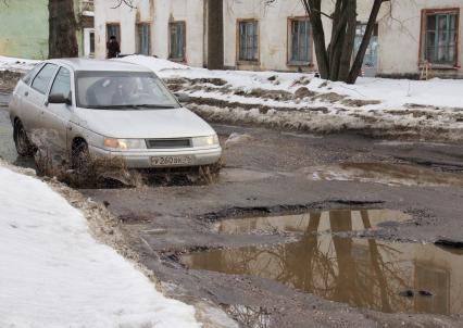 Ямы на дорогах в городе, автомобиль едет по ямам.