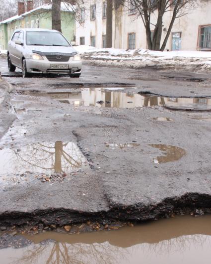 Ямы на дорогах в городе, автомобиль едет по ямам.