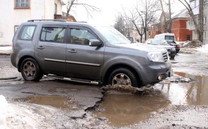 Ямы на дорогах в городе, автомобиль едет по ямам.