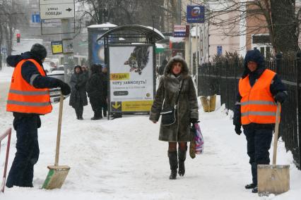 Дворники чистят тротуар от снега.