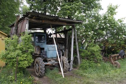 Трактор под навесом в деревне.