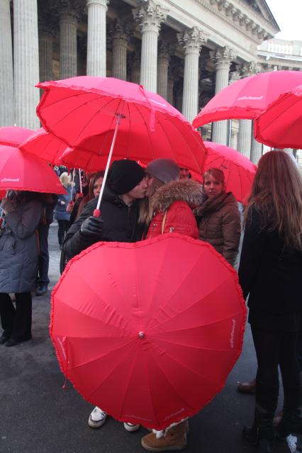 Акция в Санкт-Петербурге `Сердце города 2012` На снимке: девушка и юноша целуются стоя под красным зонтом в форме сердца.
