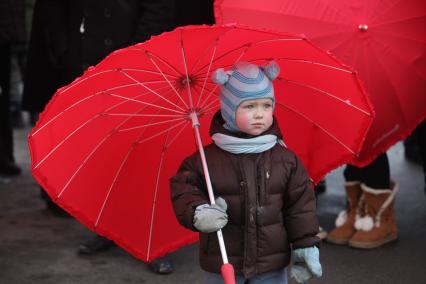Акция в Санкт-Петербурге `Сердце города 2012` На снимке: ребенок под красным зонтом.