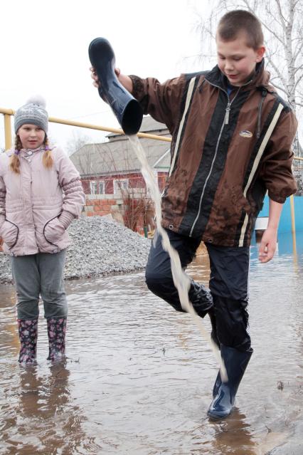 Ребенок выливает воду из резиновых сапог.