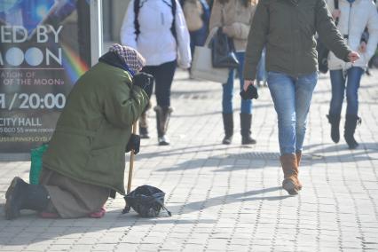 Нищенка просит милостыню на городской улице.