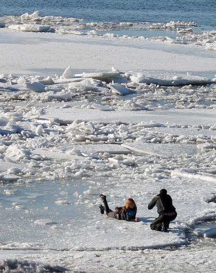 Начало ледохода на Волге. Девушка позирует фотографу лежа на льдине.